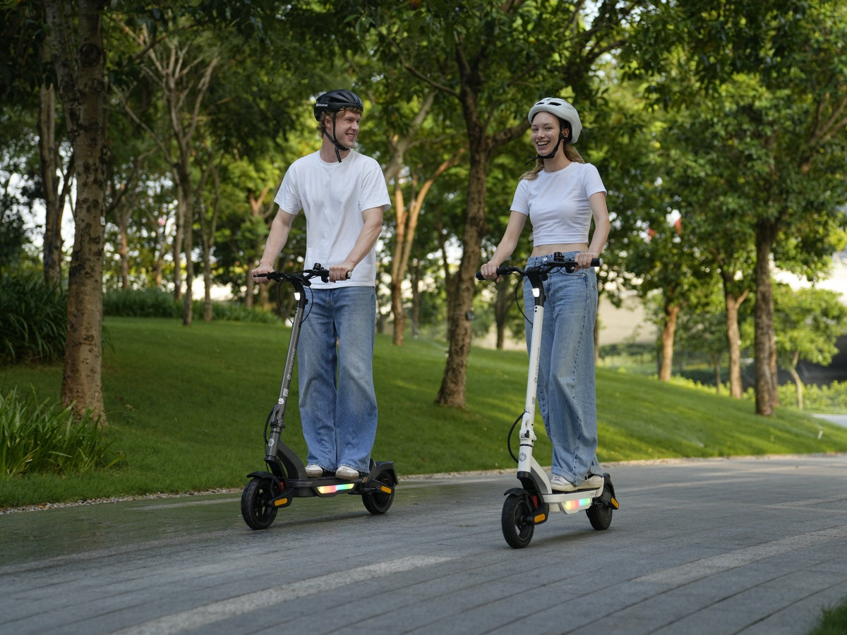 Two riders on iSinwheel S Nova scooters on a tree-lined park path