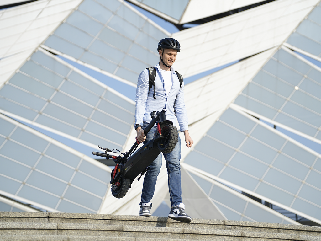 Rider carrying the folded iSinwheel GT2 beside a glass building