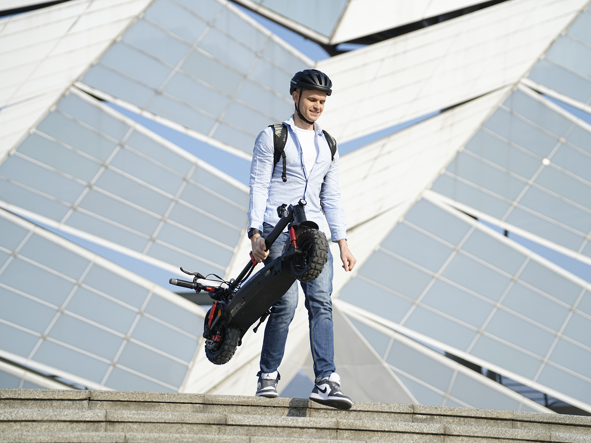 Rider carrying the folded iSinwheel GT2 beside a glass building