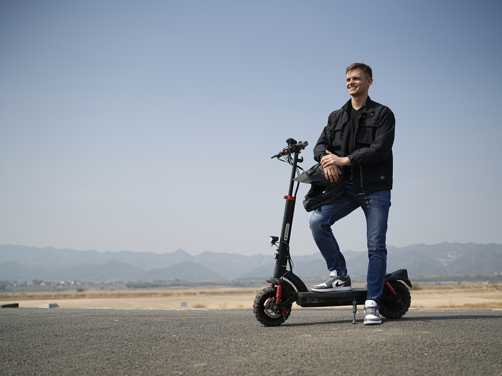 Rider standing beside the iSinwheel GT2 with mountains behind