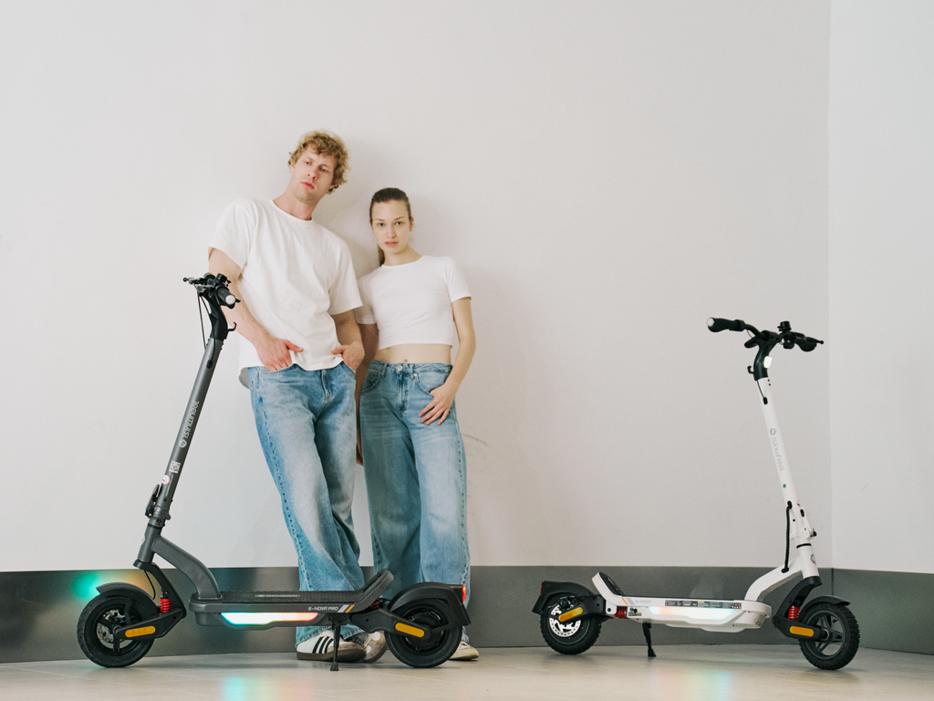 Two riders standing between iSinwheel S Nova scooters in Gray and White